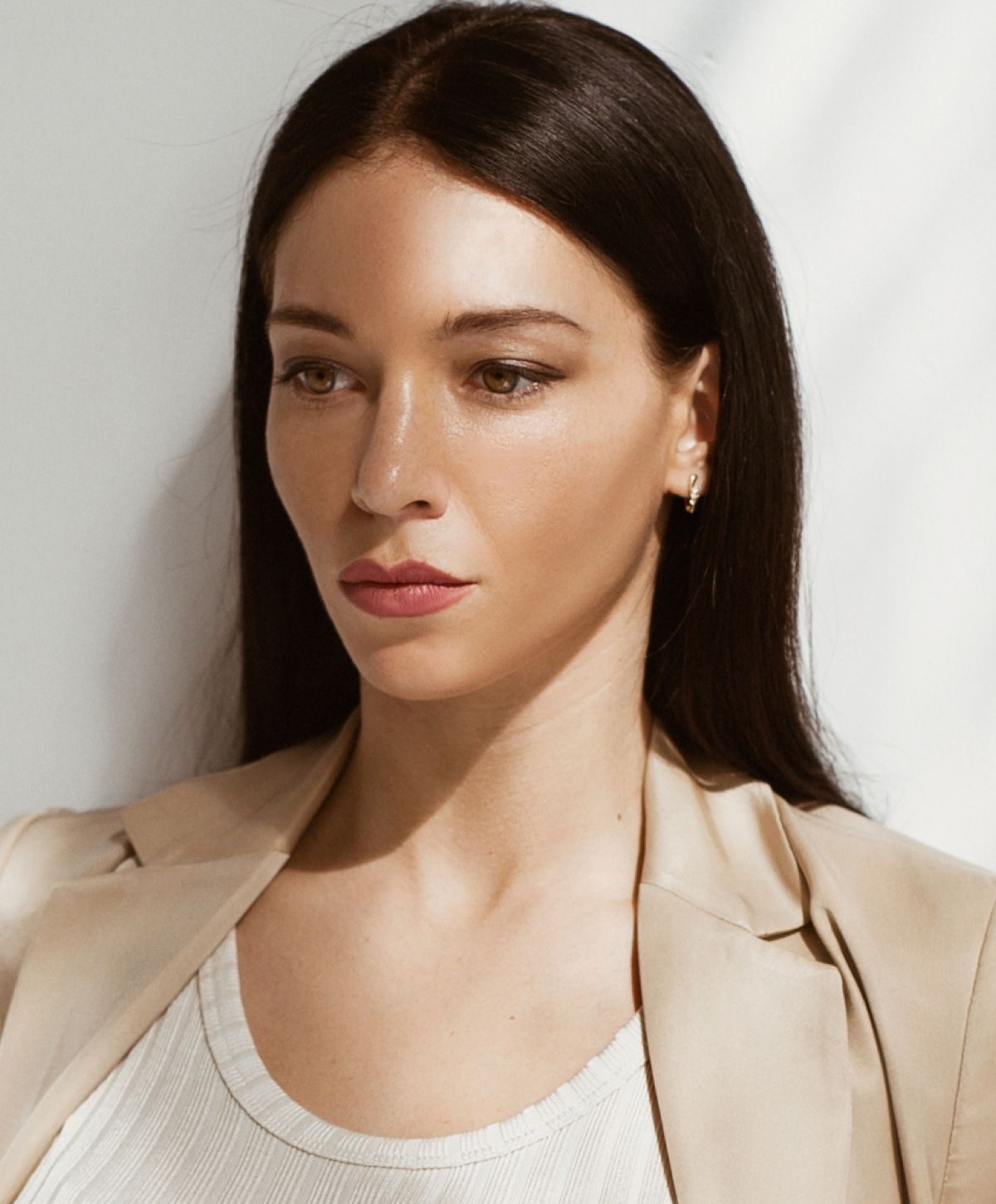 Woman in light blazer with serious expression.