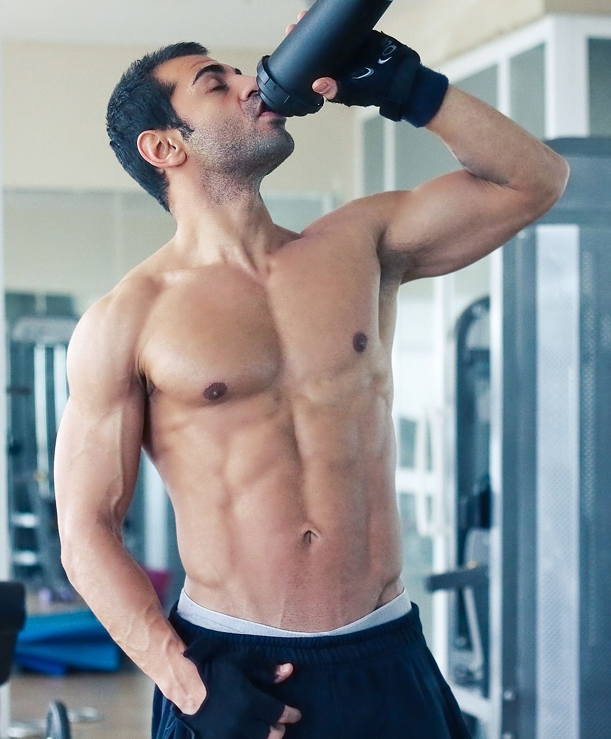 Man drinking from a shaker in gym setting