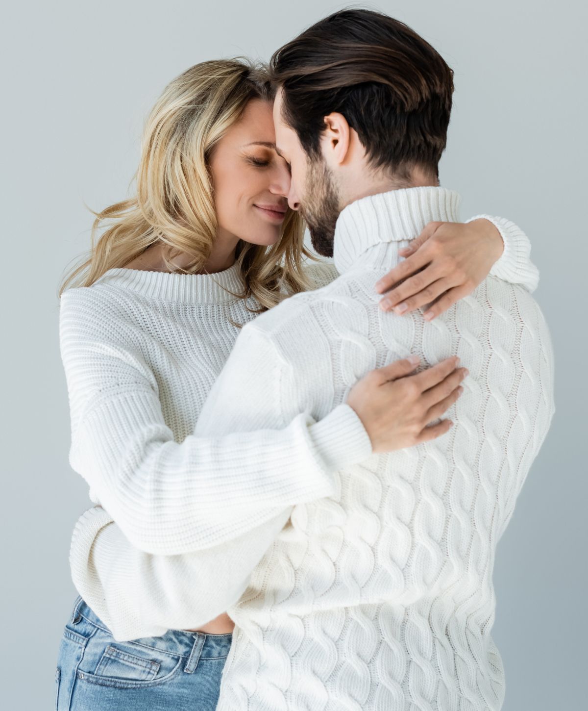 Couple embracing in cozy sweaters, enjoying moment.