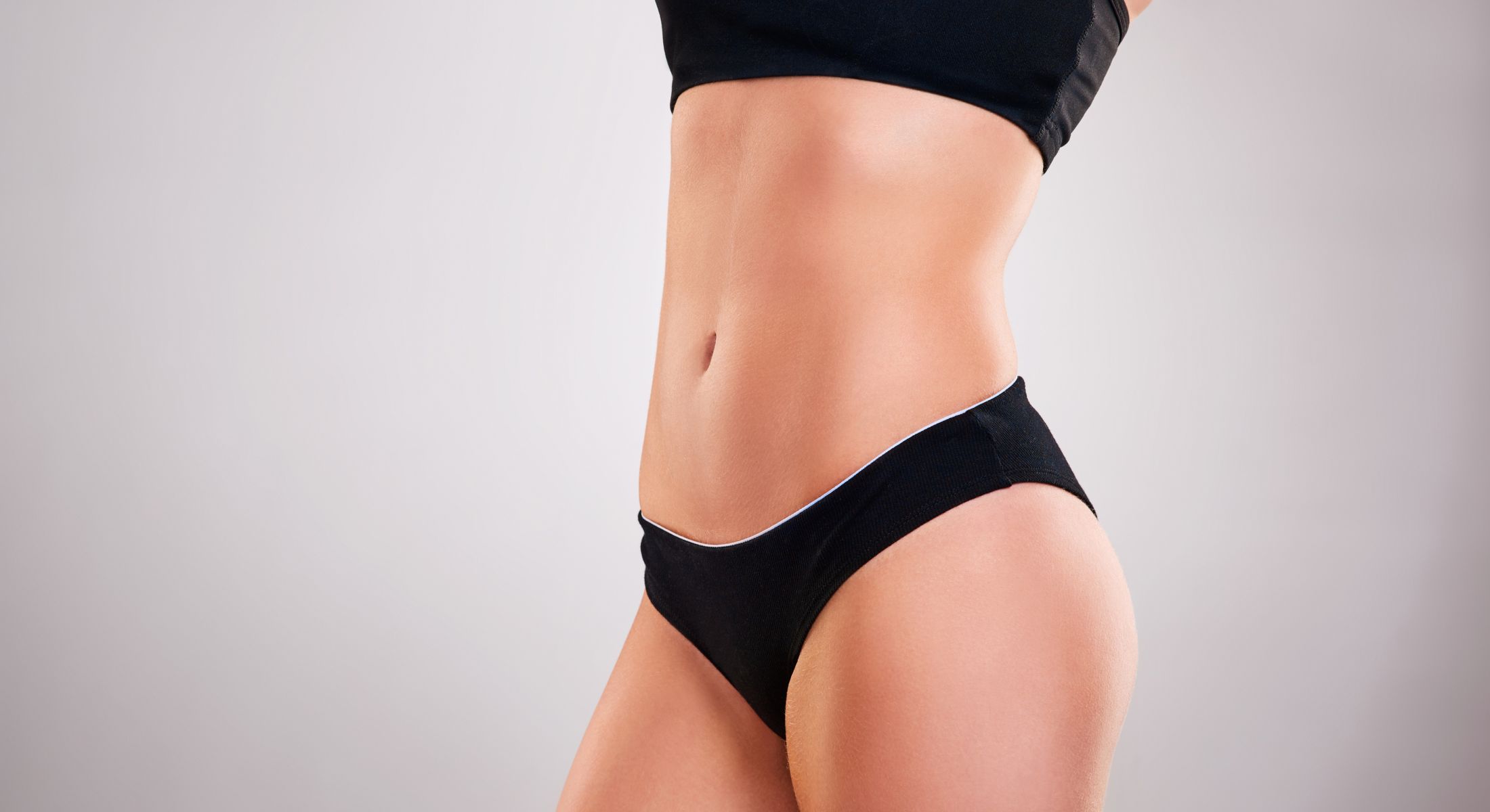 Model in black sportswear showcasing toned midsection.