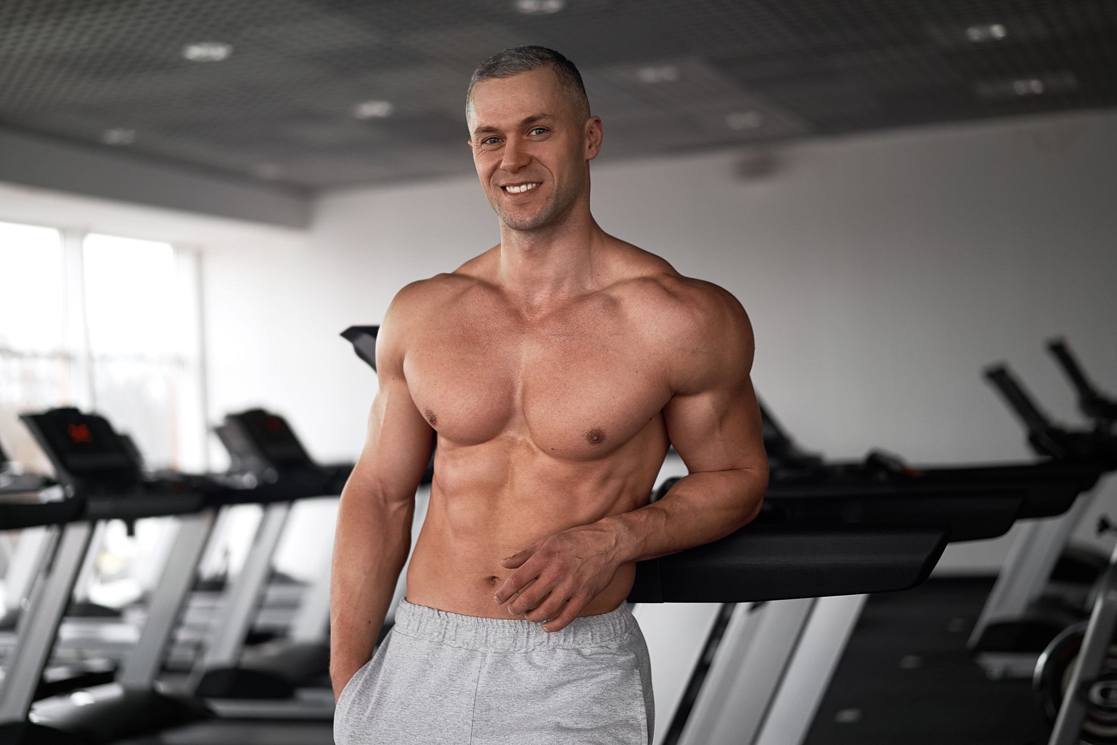 Muscular man smiling in a gym setting.